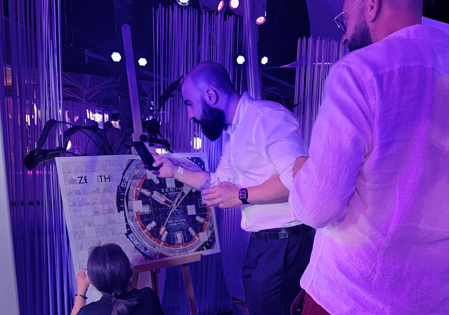 Guests watching as their photos build a branded mosaic wall during a photo booth activation in Malta